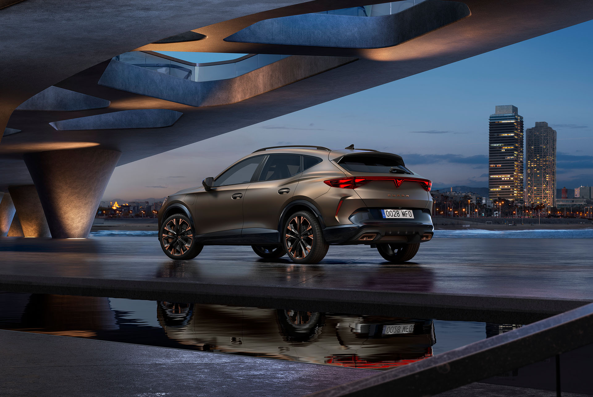 Uus hübriidauto CUPRA Formentor, vaade vee äärde pargitud autole vildakuti tagant, taustal linna siluett. Tänu vaatenurgale on hästi näha auto tagaosa disain, tuled ja sportlikud topelt-väljalasketorud.